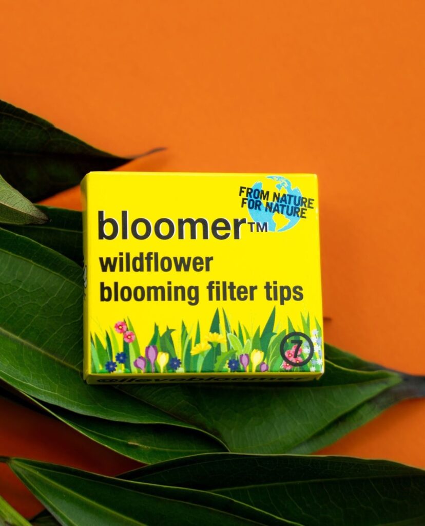 Bloomer Plantable Wax Filter Tips resting on a green leaf, symbolizing eco-friendly smoking accessories that support pollinator conservation, The New Bee Saving Accessory: Bloomer™ Plantable Wax Filter Tips.