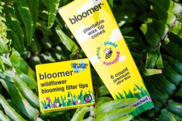 Bloomer filter tips and cones surrounded by vibrant wildflowers, promoting pollinator support and eco-friendly smoking solutions