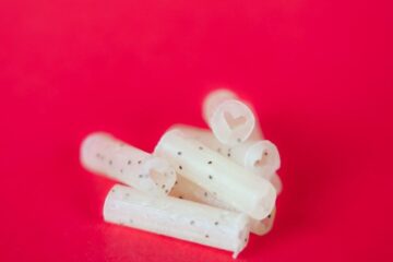 Eco-friendly Bloomer filter tips stacked on vibrant red background, showcasing biodegradable smoking accessories for pollinator conservation